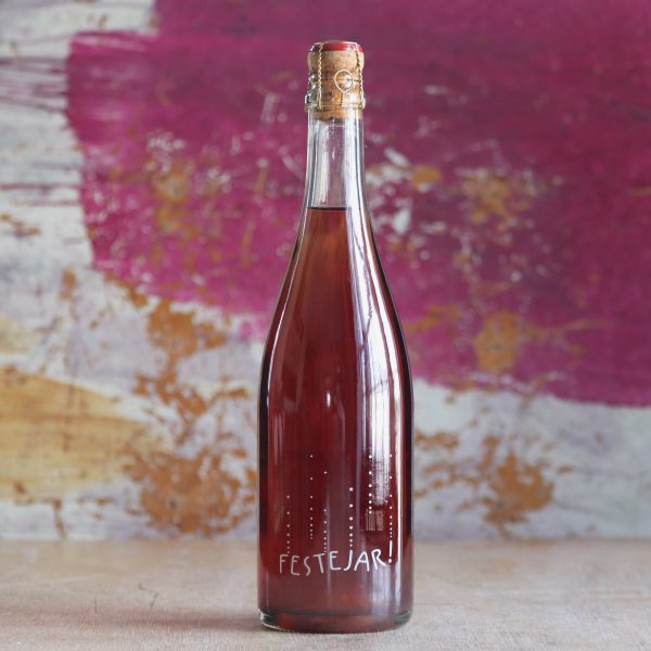A bottle of Patrick Bouu 'Festejar' in front of a colourful background